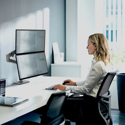 Ergotron LX Pro w nowoczesnym biurze. Uchwyt na monitor do biurka w układzie pionowym zwiększa przestrzeń roboczą i poprawia ergonomię pracy przy dwóch ekranach.