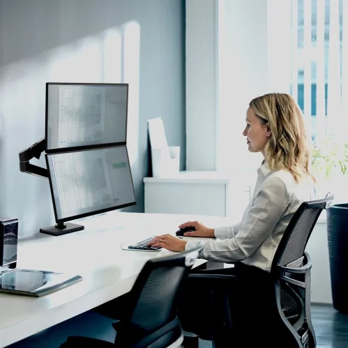 Ergotron LX Pro czarny w nowoczesnym biurze. Uchwyt do monitorów na biurko w układzie pionowym zwiększa ergonomię i pomaga utrzymać porządek na stanowisku pracy.