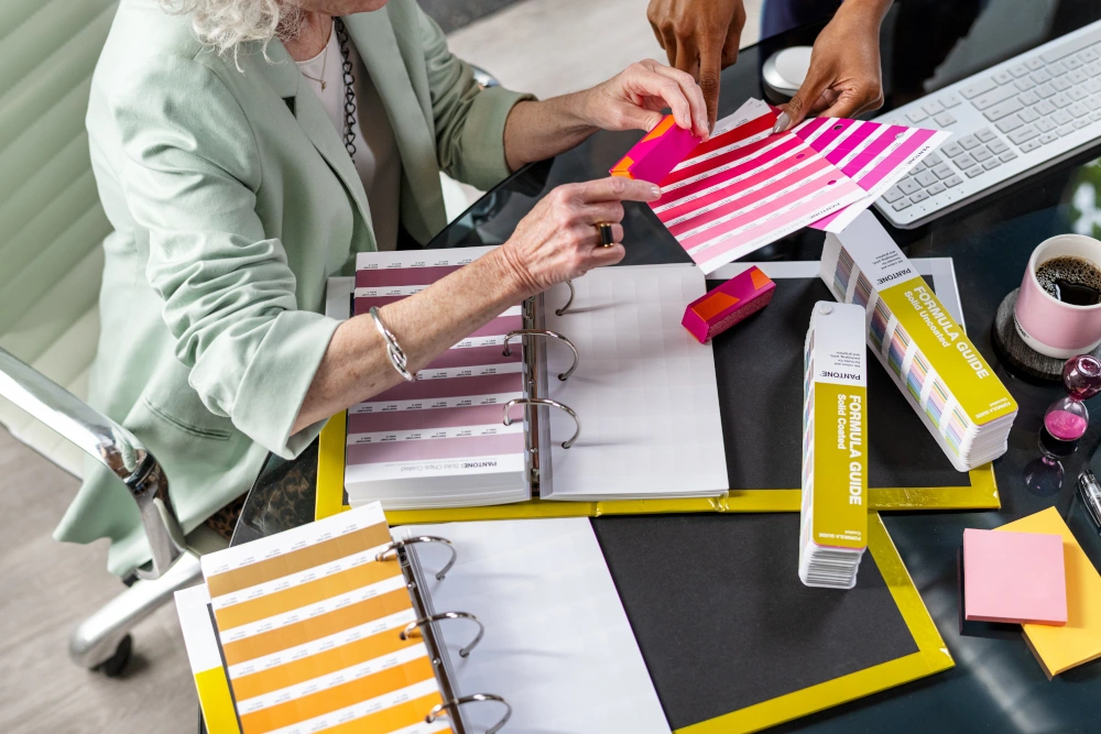 Zespół projektowy korzystający z Pantone Reference Library, wzorników Pantone i segregatorów z odrywanymi chipami